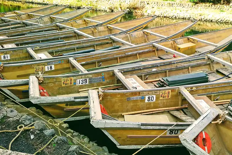 Hozugawa boats moored at the Arashiyama end — flat-bottomed, wooden, poled down from Kameoka
